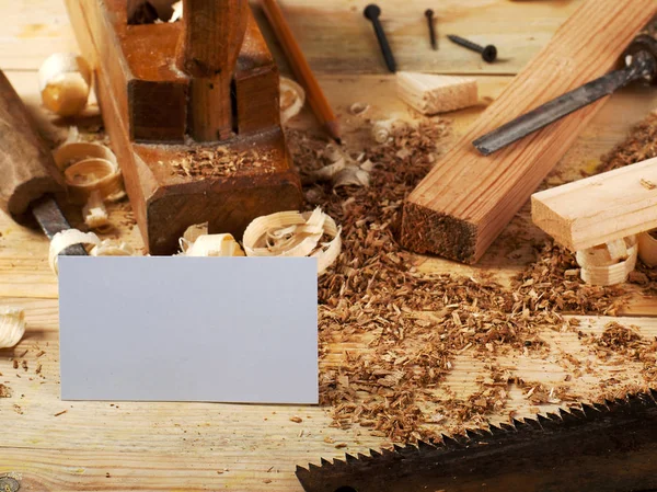 Vizitka na dřevěný stůl pro tesařské nástroje s pilinami. — Stock fotografie