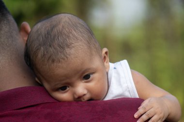 Bebek, sakin bir ortamda erkeğin omzunda rahatlar.