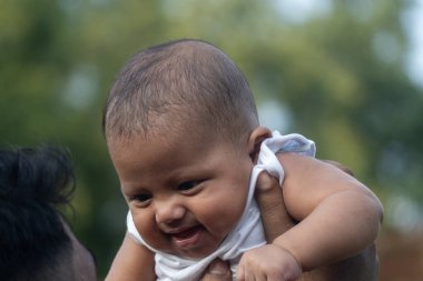 Bebek kaldırılıyor ve dışarıda neşeyle gülümsüyor.