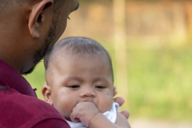 Bebek sakince yere bakar, dışarıda nazik bir adam tarafından tutulur.