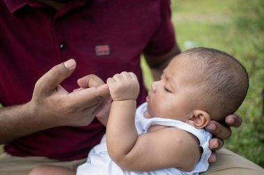 Düşünceli bebek bir erkeğin parmaklarıyla içeride etkileşime girer.