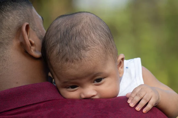 Bebek bir erkeğin omzunda huzur içinde yatar.