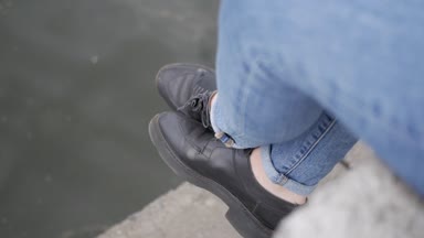 Genç bir kız nehir dolgu üzerinde oturuyor