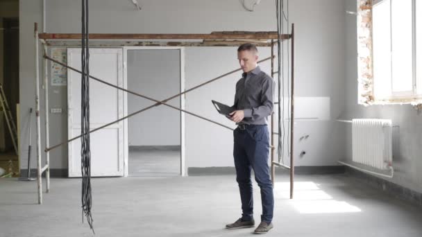 Un hombre inspecciona la reparación en interiores — Vídeo de stock