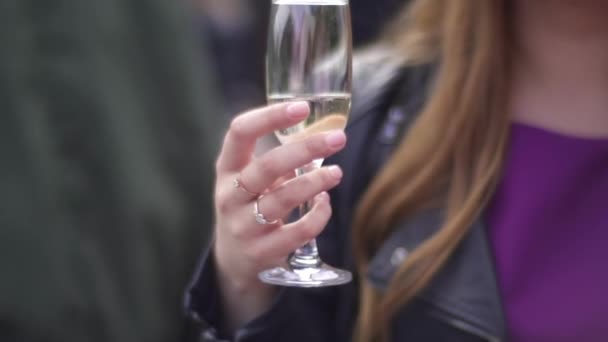 En flicka håller ett glas champagne i sina händer — Stockvideo