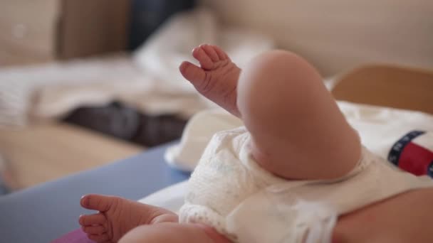 Kleines Baby liegt mit Stoffwindel auf dem Sofa und tritt gegen die Beine — Stockvideo