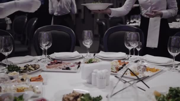 服务员在餐厅端上的菜和沙拉放盘子 上面覆盖着白色桌布 餐具和菜肴都放在咖啡馆里的桌子上 在桌子上供应凯撒沙拉 — 图库视频影像