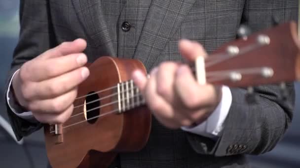En man i kostym spelar ukulele — Stockvideo