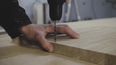 Bir adam ahşap kütükte delik açar.