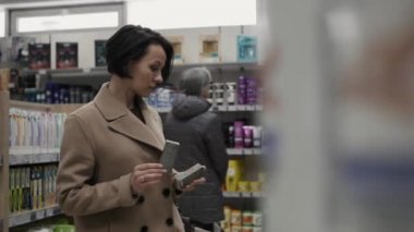 güzel bir kadın kozmetik süpermarkette bakarak.