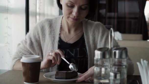 Hermosa morena bebe café de una taza y comer pastel de queso — Vídeo de stock