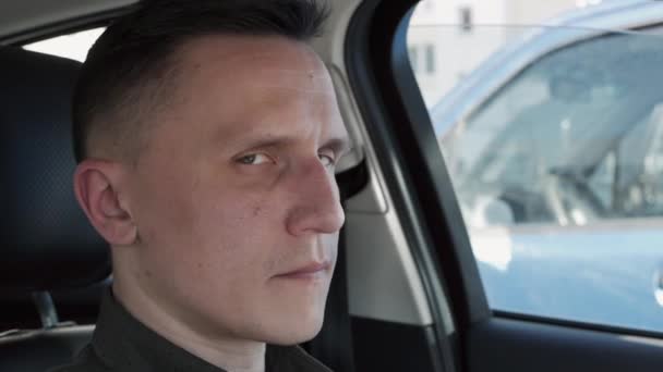 Portret van een man die in een auto zit. Hij kijkt naar de camera. — Stockvideo