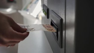 Bir kadının eli Atm'ye banknot yapar.