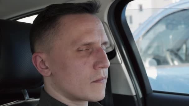 Portret van een man die in een auto zit. Hij kijkt naar de camera. — Stockvideo