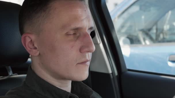 Porträt eines Mannes, der in einem Auto sitzt. er blickt in die Kamera. — Stockvideo