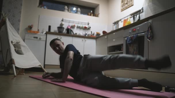 Knappe man trainen en doen push-ups in de keuken thuis — Stockvideo