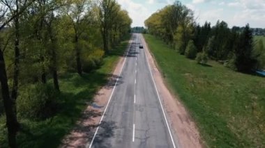 Drone ağaçların arasındaki yolda uçuyor ve arabaları izliyor.