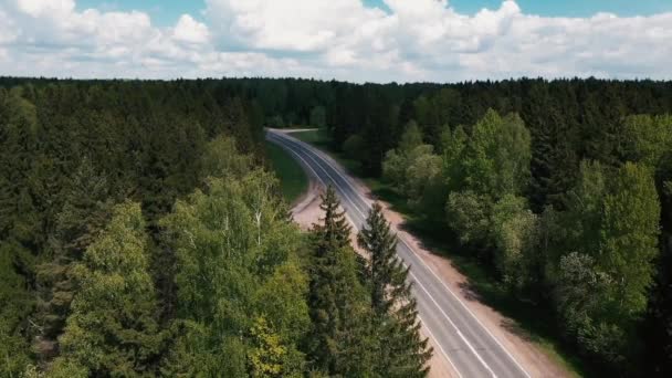 O drone voa sobre a estrada entre as árvores e observando os carros — Vídeo de Stock