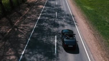 Drone ağaçların arasındaki yolda uçuyor ve arabaları izliyor.