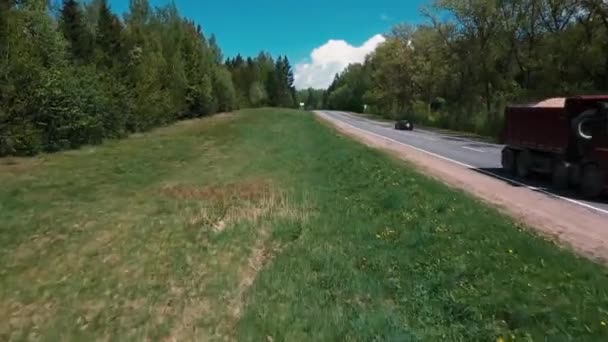 O drone voa sobre a estrada entre as árvores e observando os carros — Vídeo de Stock