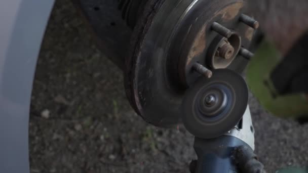 The mechanic cuts the wheel of the car with a grinder — Stock Video