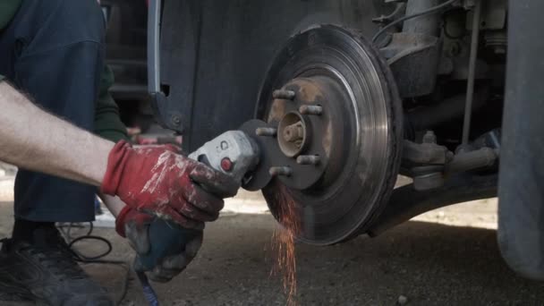 Mechanik tnie koło samochodu za pomocą młynka — Wideo stockowe