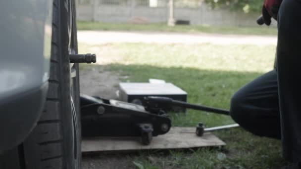 Le constructeur dévisse les boulons de roue pour enlever la roue de la voiture . — Video