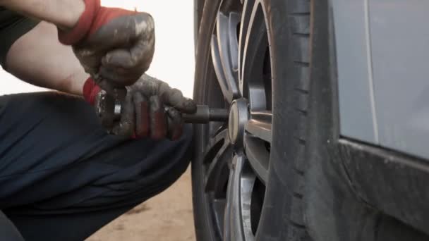 El fabricante de automóviles desenrosca los tornillos de la rueda para quitar la rueda del coche . — Vídeo de stock