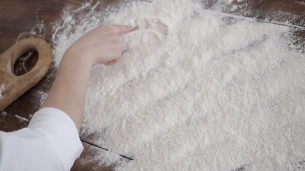 男と女が小麦粉でテーブルの上に手紙を描く. — ストック動画