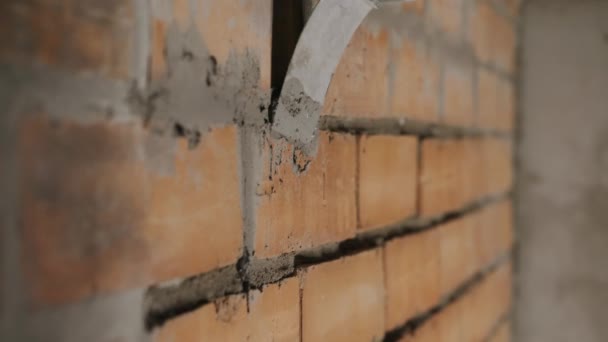 Le constructeur applique du mortier de ciment sur le mur de briques.