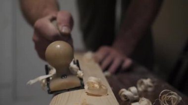 Bir adam el uçağıyla tahtayı yontuyor..