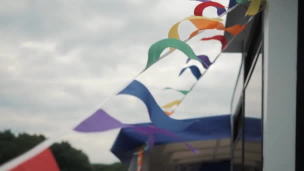Veelkleurige vlaggen hangend aan een touw fladderen in de wind — Stockvideo