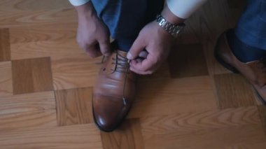 Bir adam ayakkabı bağcıklarını deri ayakkabılarla bağlar.