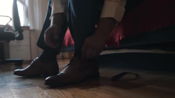 Egy férfi bőrcipőbe köti a cipőfűzőjét. — Stock videók