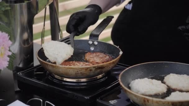 Повар жарит картофельные блинчики на двух сковородках.. — стоковое видео