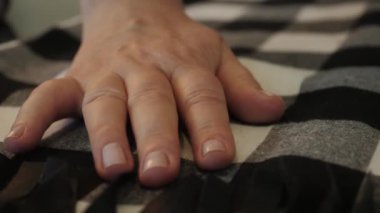 Bir kadının eli kumaşın üzerinden kayar..