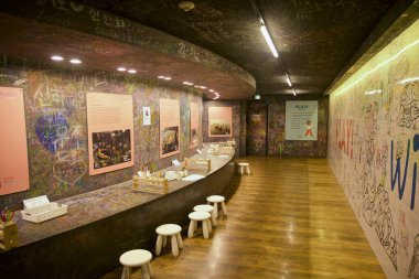 Karatahta duvarlarla kaplı uzun kıvrımlı koridor ziyaretçileri, oyuncak ayı müzesinin içindeki sıcak ışıkların altına dışkılar ve sanat malzemeleriyle mesaj bırakmaya ve çizmeye davet ediyor..