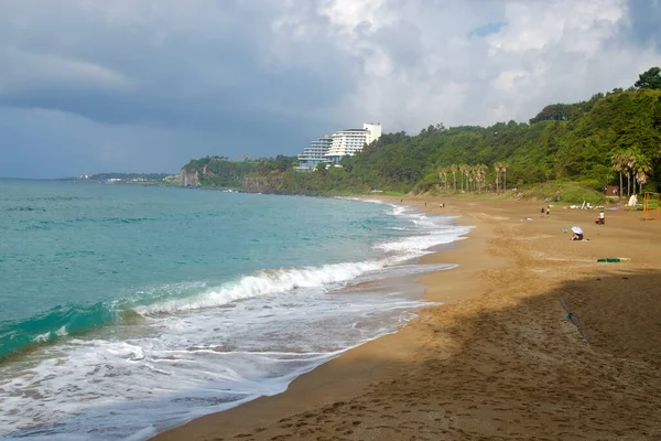 Jungmun Saekdal Sahili boyunca geniş bir Jinmosal kumdan oluşan dalgalar ve değişen gökyüzünün altındaki volkanik kayalıklara tünemiş bir tatil beldesi görülüyor..