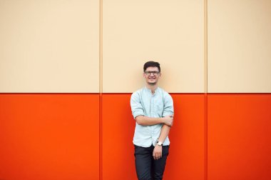 Turuncu bir duvardan gülümseyen yakışıklı adam