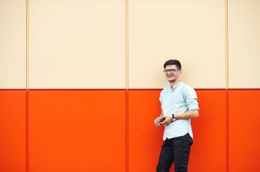 Turuncu bir duvardan gülümseyen yakışıklı adam