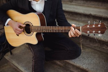 Gitar çalmak rahat kıyafetle dostum, kapat. Genç hipster merdivenlerde siting