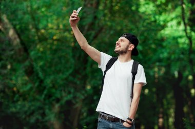 Şık mutlu hipster beyaz tshirt ve bir selfie ile smartphone çekerken gülüyor moduna ile görüntü.