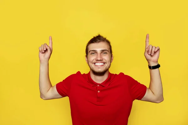 Retrato de un hombre barbudo feliz apuntando con los dedos hacia arriba en el copyspace aislado sobre el fondo amarillo . — Foto de Stock