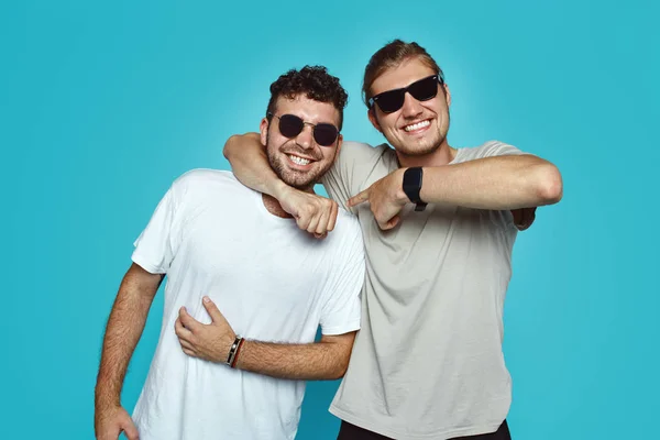 Dwóch mężczyzn młodych hipster mieć dobre stosunki i przyjaźni prawdomówny, embarce siebie i gladfully uśmiech na niebieskim tle — Zdjęcie stockowe