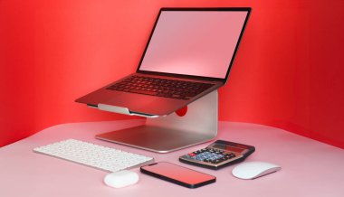 Laptop ve akıllı telefon masada. Temiz boş ekran modeli. Kırmızı arkaplan.