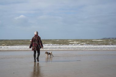 Yaşlı bir kadın kış aylarında kumsalda yürür