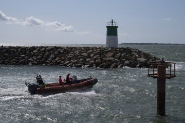 Bir gemi iki deniz feneri arasındaki limandan ayrılıyor.