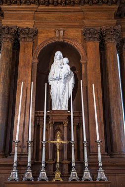 Eski bir kilisede oyulmuş ahşap bir duvara karşı Bakire Meryem heykeli.