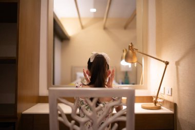 Genç kız aynaya bakıyor. 