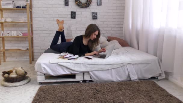 年轻女子在床上使用笔记本电脑工作 漂亮的女孩在家里用电脑学习 — 图库视频影像
